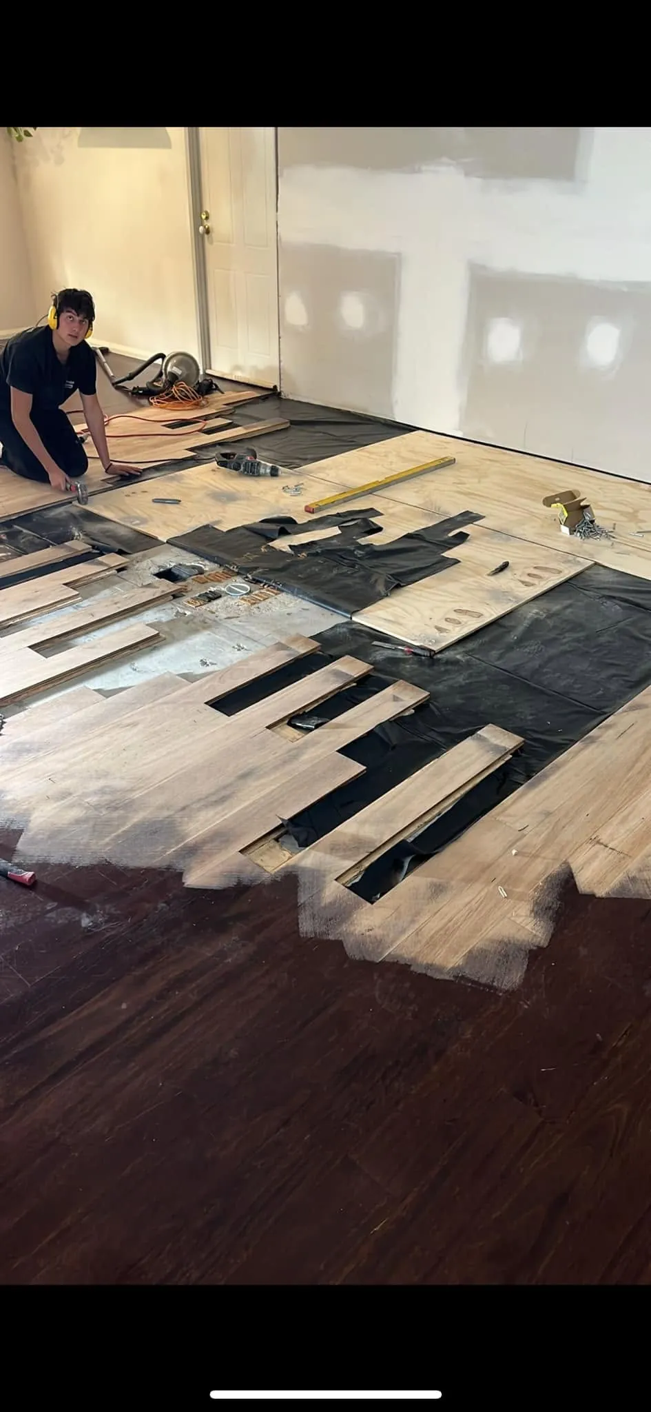 Floorboards being cut and fitted into a patched section of old flooring
