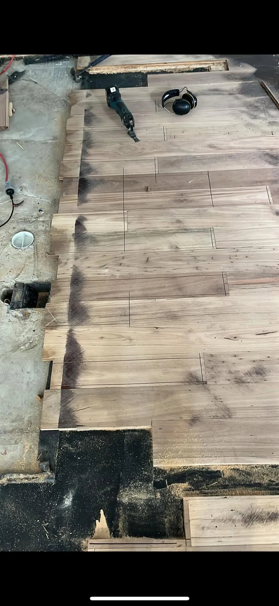 Replacement floorboards being cut into an old floor, the joists exposed beneath and tools resting alongside