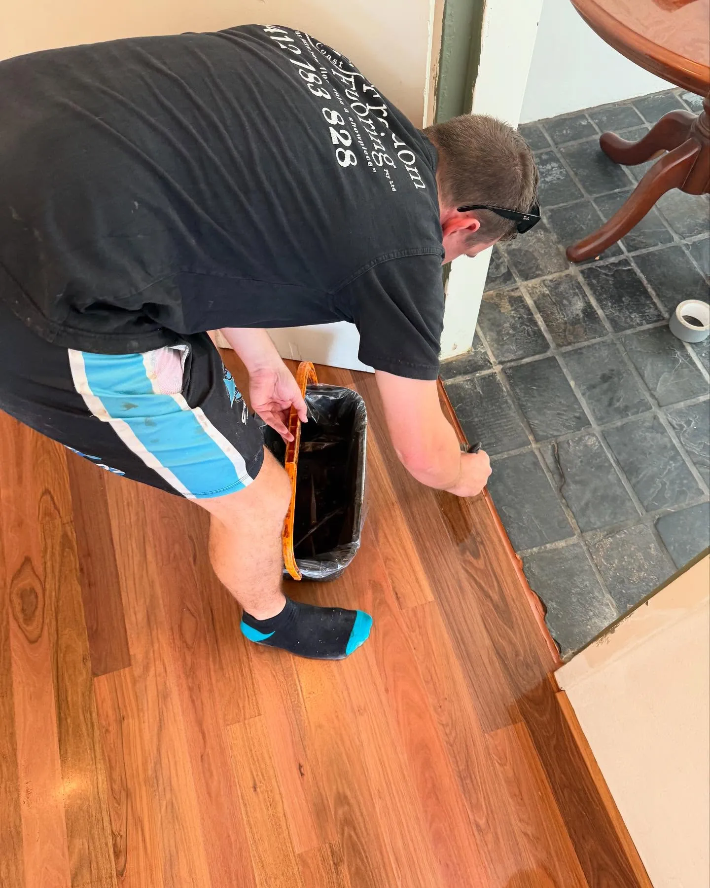 A freshly coated timber floor meeting a slate tiled area along a clean edge