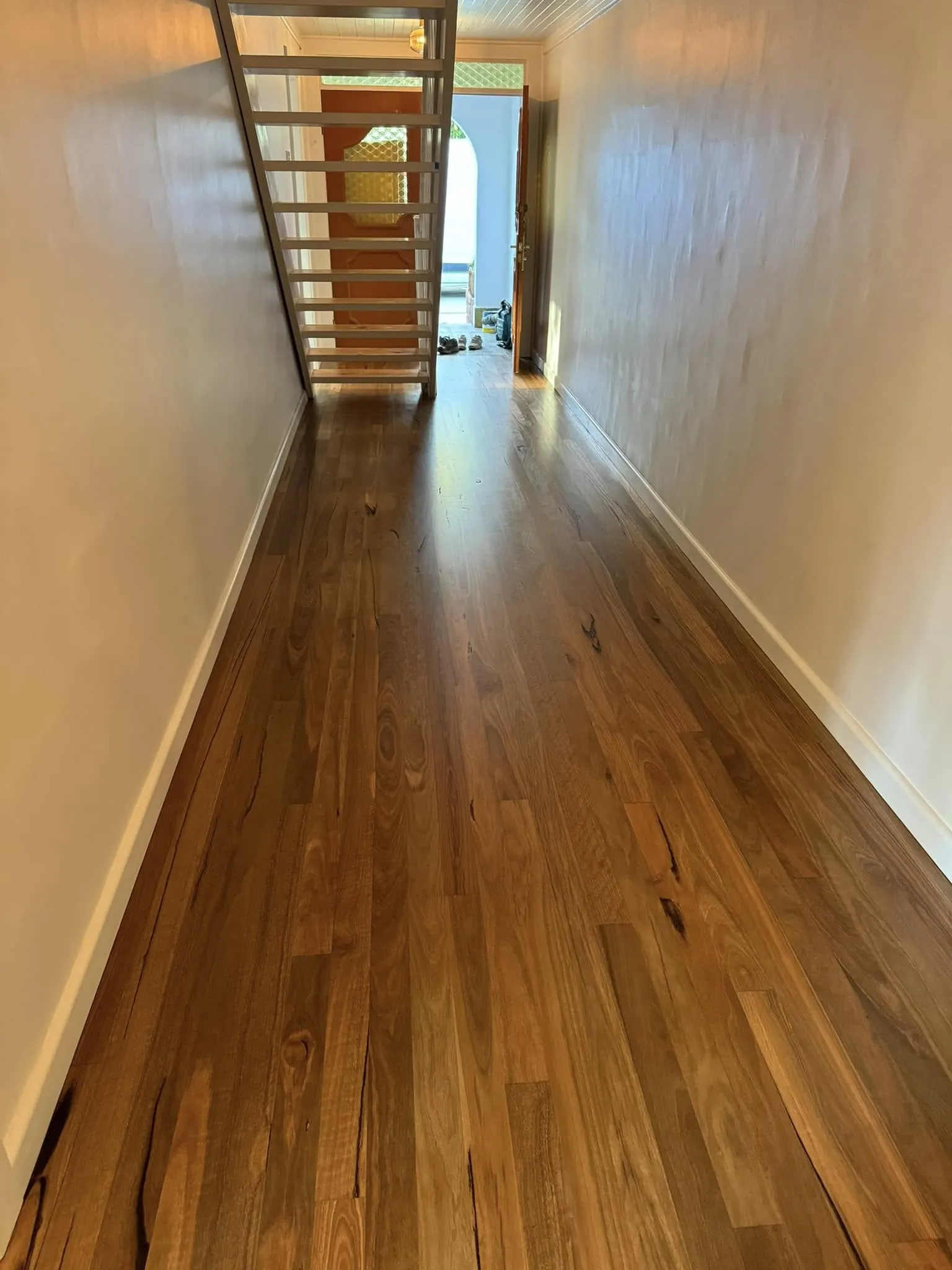 A polished timber hallway floor running toward an open staircase